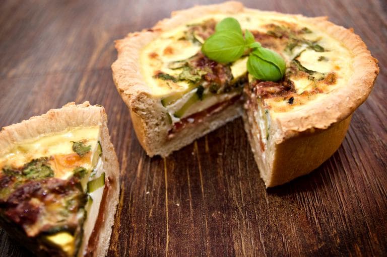 A delicious deep layered Mediterranean quiche with basil garnish